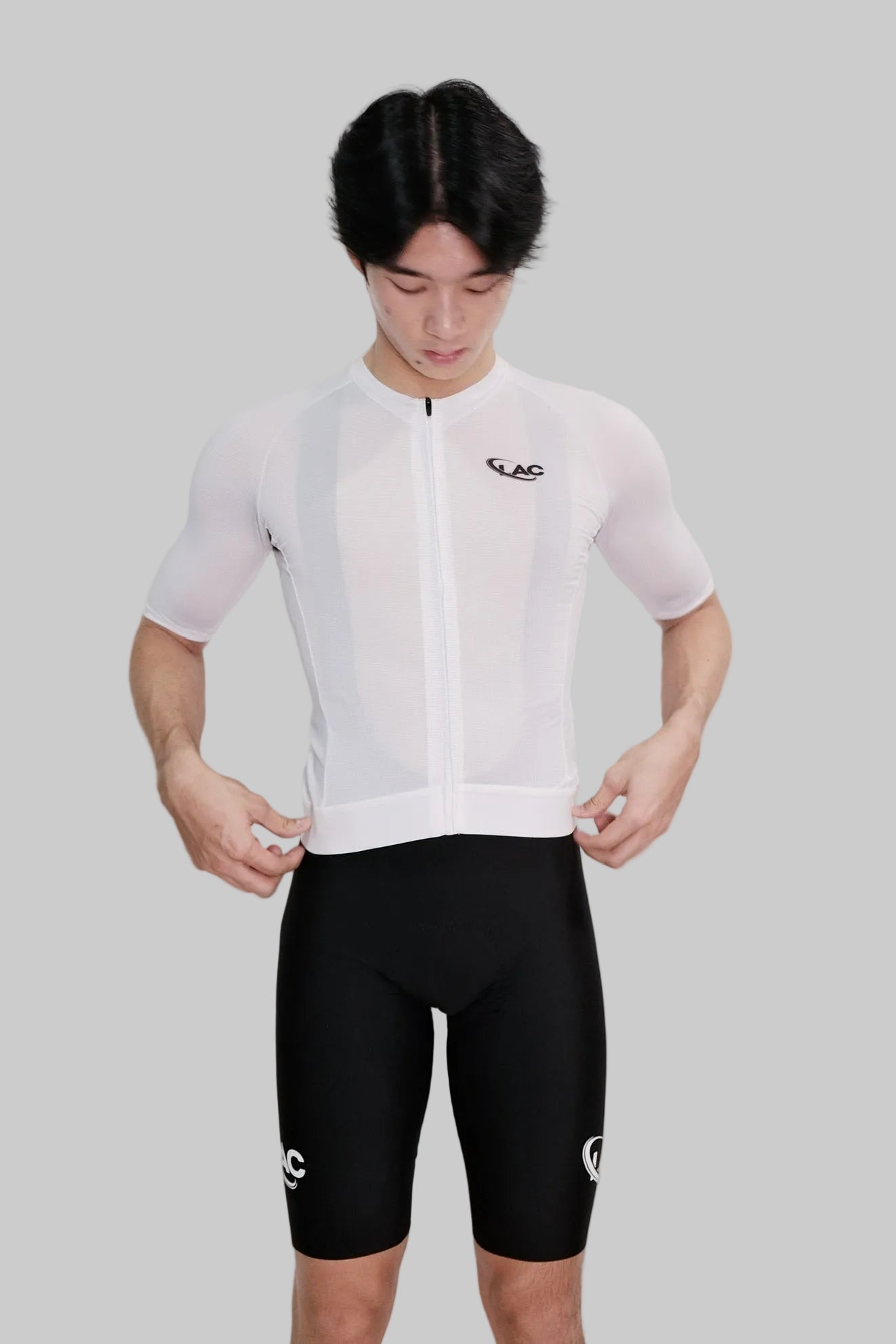 Person wearing a white cycling jersey and black shorts with a visible brand logo on a white background