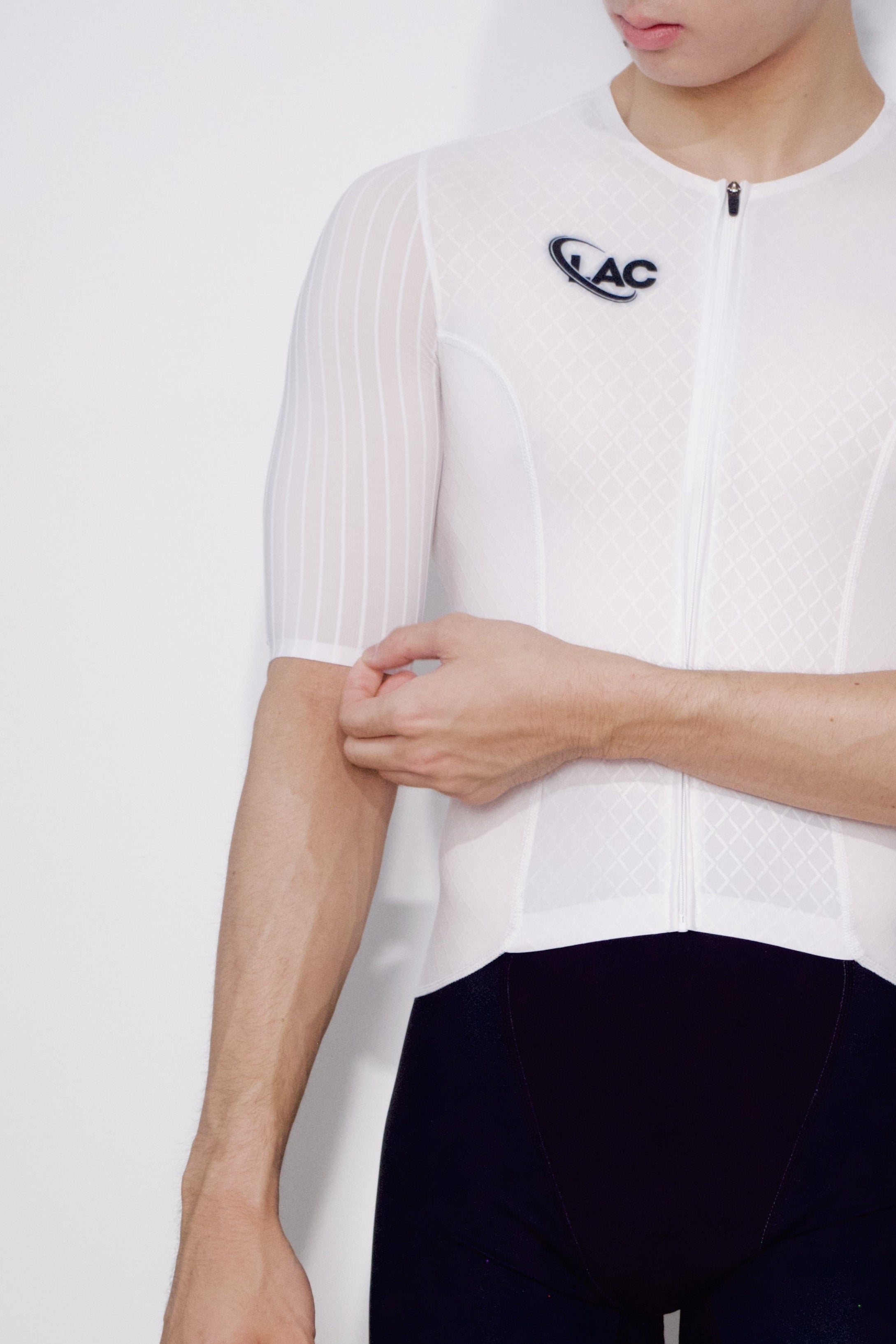 Person wearing a white cycling jersey and black shorts with a brand logo on a white background
