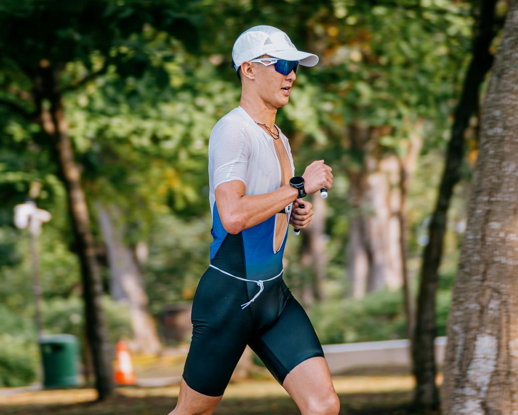 Man running on a path in a park with trees and greenery.
