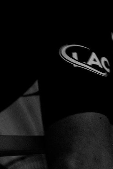 Black glove with a logo on a person's hand, wearing a striped shirt.